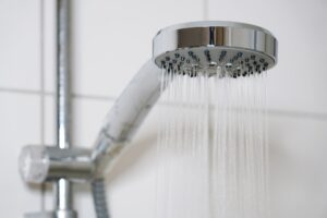 shower with modern showerhead and running water in domestic bathroom close-up